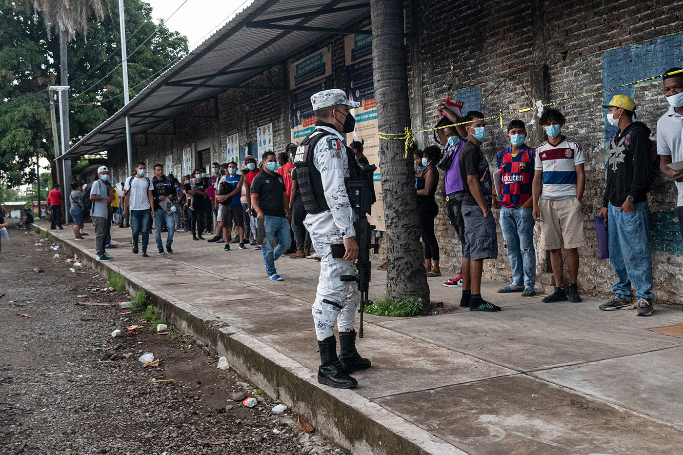 Elementos de la Guardia Nacional custodian filas de personas migrantes que buscan una cita en la Comar. 
